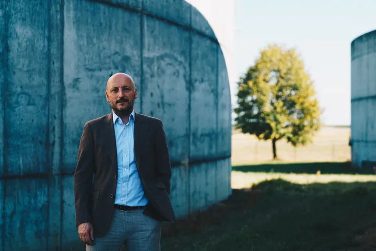 Andreas B. im Sakko vor den Betonbehältern der Biogasanlage in Ziersdorf