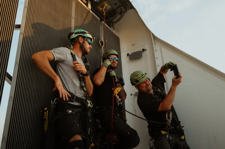 Drei Industriekletterer von RTS Wind in Gurt und Helm auf dem Gondeldach