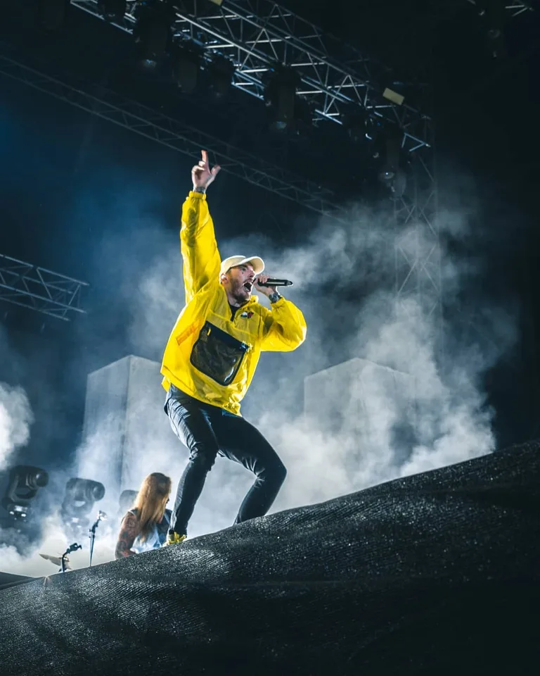 Konzertfotografie: Rapper in gelber Jacke auf der Bühne, Bühnennebel und Traversen
