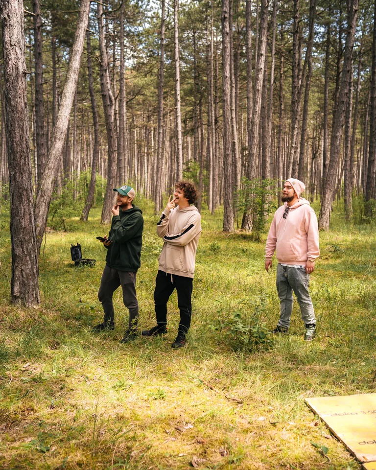Drei Crew-Mitglieder lachen am Set im Föhrenwald, Musikvideo „Walls“ für AVEC