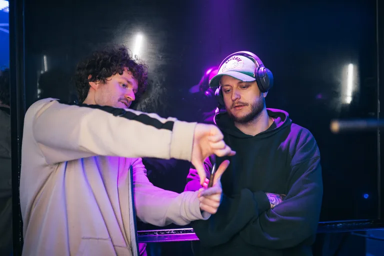 Musikvideo-Dreh: zwei Crew-Mitglieder besprechen eine Einstellung, violettes Set-Licht