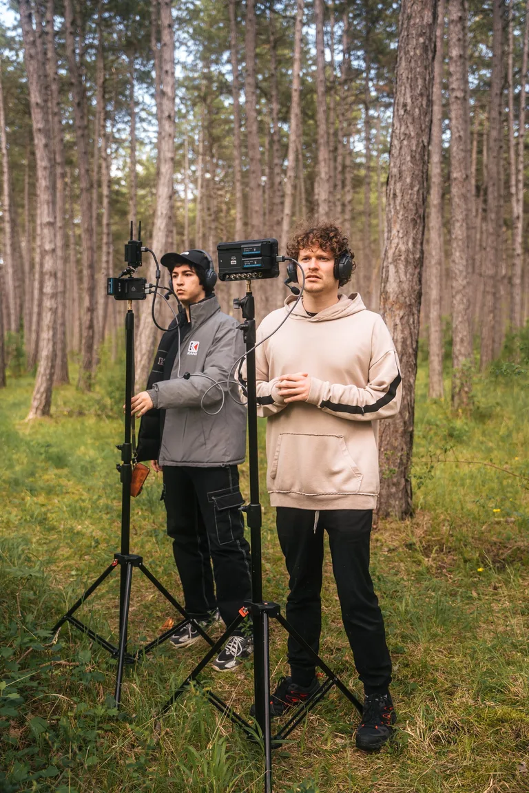 Am Set im Wald: zwei Crew-Mitglieder mit Kopfhörern an Monitoren auf Stativen